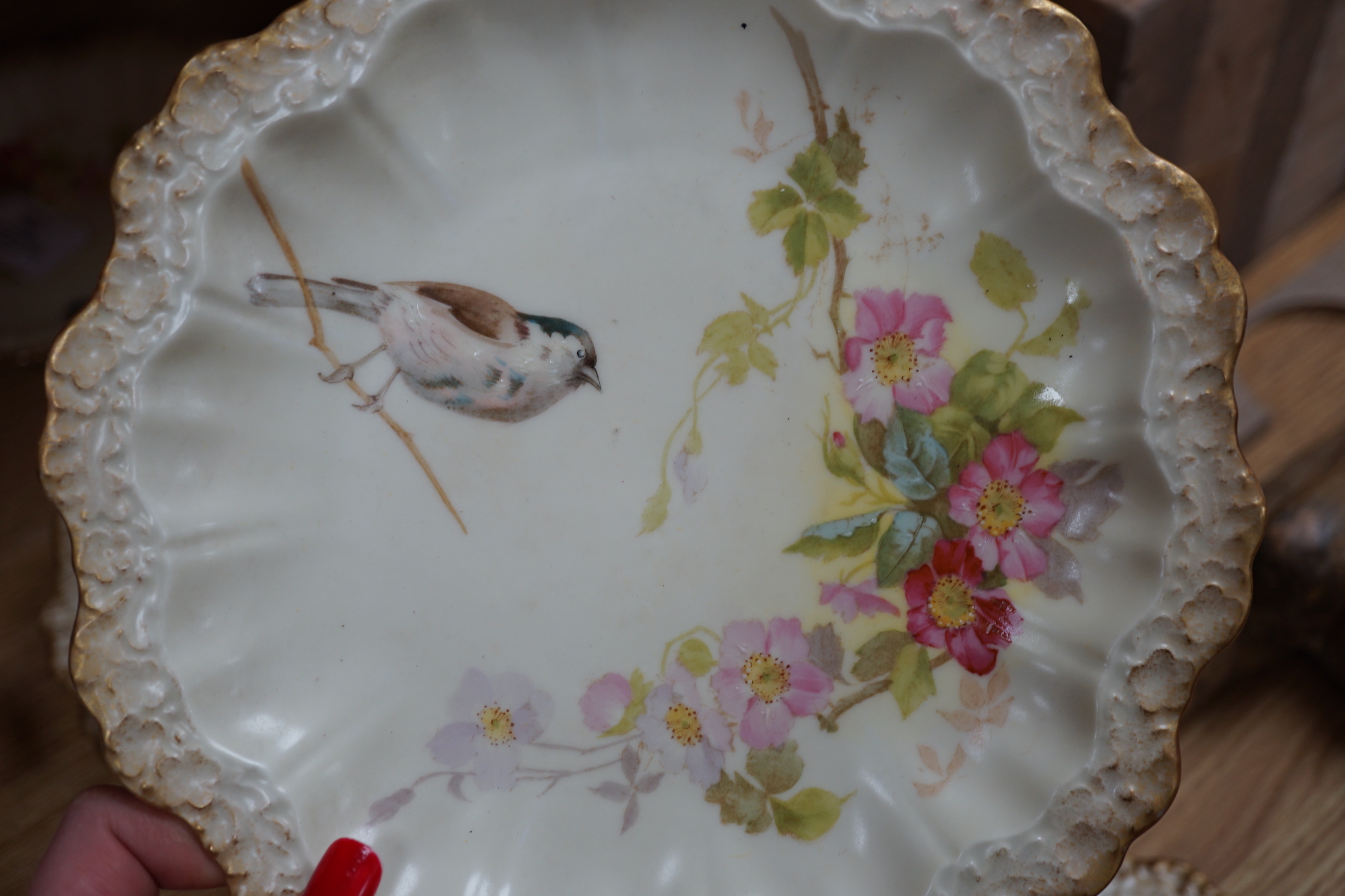 A Limoges dessert service decorated with birds and flowers, the largest 27cm wide